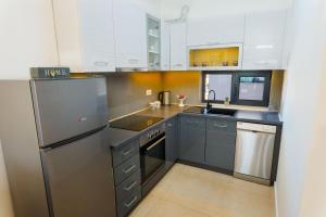a kitchen with white cabinets and a stainless steel refrigerator at Harizma apartmani - Maja in Kragujevac
