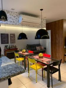 a living room with yellow chairs and a table at Apartamento completo no Guarujá in Guarujá