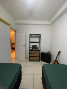 a room with two beds and a mirror and a guitar at Apartamento completo no Guarujá in Guarujá +11 photos