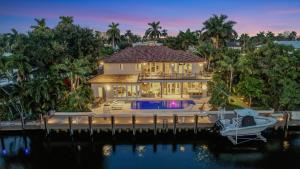 una casa en un muelle con un barco en el agua en Elegant Waterfront Estate 6BR- 6.5BA, en Fort Lauderdale