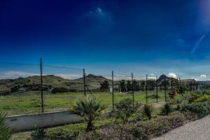 a fence in a field with mountains in the background at B&B L'EDEN DI CAPO BIANCO in Montallegro