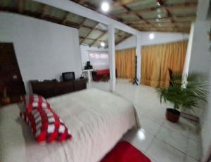 ein Schlafzimmer mit einem großen Bett mit einem rot-weißen Kissen in der Unterkunft Nebraska's Corner cerca de aeropuerto de Tababela in Yaruguí