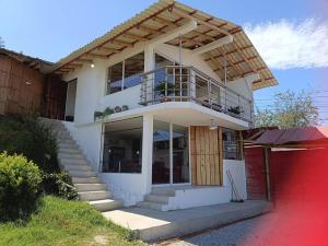 a white house with a balcony and a red garage at Nebraska's Corner cerca de aeropuerto de Tababela in Yaruguí