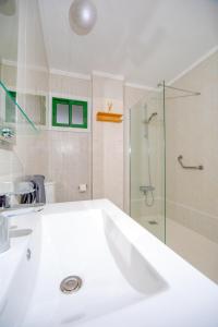 a white bathroom with a shower and a sink at 1 bedroom for 4 people with pool Puerto de la Cruz in Puerto de la Cruz