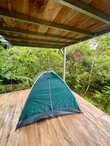 a green tent sitting on a wooden deck at Corcovado Camping in Puerto Jiménez