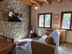sala de estar con sofá y chimenea de piedra en Alojamientos Ruraltena, en Piedrafita de Jaca