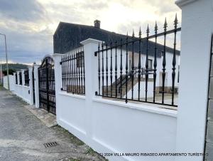biały płot z czarnymi bramami na ulicy w obiekcie Villa Mauro Ribadeo Apartamento Turístico w mieście Ribadeo