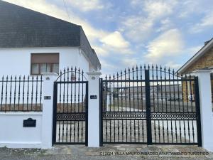 Biały dom z czarną bramą przed nim w obiekcie Villa Mauro Ribadeo Apartamento Turístico w mieście Ribadeo