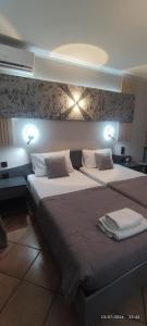 two beds in a bedroom with lights on the wall at olivegrove in Sidari