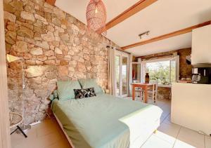 Un dormitorio con una pared de piedra y una cama en Le Mazet en Provence 25m2, en Le Tignet