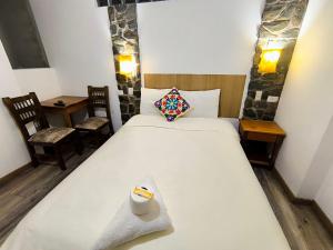 a bedroom with a large white bed and two chairs at hostal Balcon de Piedra in Urubamba