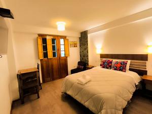 a bedroom with a bed and a desk and a chair at hostal Balcon de Piedra in Urubamba