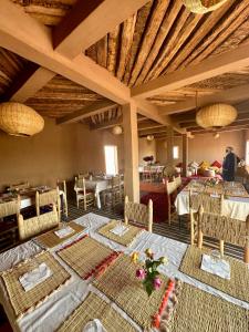 una sala da pranzo con tavoli, sedie e soffitti in legno di Bivouac Erg Chegaga Nomademoi a El Gouera
