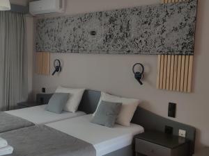 two beds in a hotel room with a picture on the wall at olivegrove in Sidari