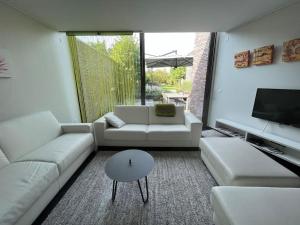 a living room with white couches and a tv at Vakantiehuis Tube nabij Brugge in Bruges