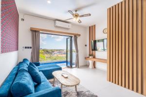 a living room with a blue couch and a window at The Peak - 2BR Luxury Hill Villa Nusa Dua in Nusa Dua