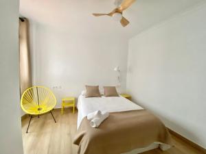 ein weißes Schlafzimmer mit einem Bett und einem gelben Stuhl in der Unterkunft Balcón de la Paz in Antequera