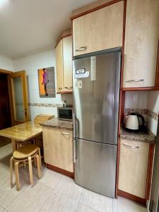 a kitchen with a stainless steel refrigerator and a table at Apartamento Marqués parking gratuito in Oviedo +17 photos
