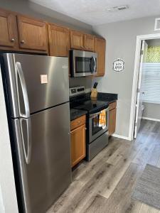 Una cocina con electrodomésticos de acero inoxidable y gabinetes de madera. en Two condos-side by side-arcade games-8 beds, en Branson