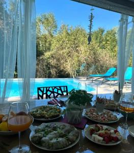a table with plates of food and drinks and a pool at Vila Green Silence in Pazin