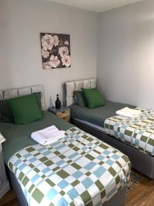 two beds sitting next to each other in a room at Everything You Need I Super Comfy I Sleeps 7 I WiFi I Parking I 4BDR in Dagenham