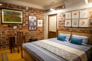 une chambre avec un lit et un mur de briques dans l'établissement Srirangam, Shantiniketan, à Srī Niketan