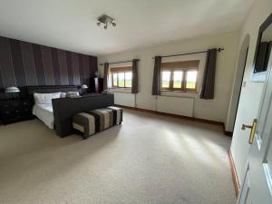 a bedroom with a bed and a couch and windows at Spacious Home, 6 large bedrooms, full sky package, sleeps 14 in Pattishall