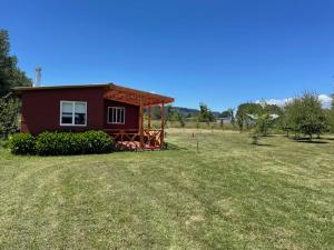 a small red house in the middle of a field at Cabaña Lago Puyehue in Mantilhue