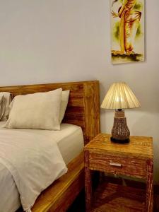 a bedroom with a bed and a table with a lamp at Uma Sindu Homestay in Sanur