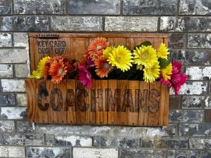 a sign on a brick wall with flowers on it at Coachman's Inn & Suites in Waldron