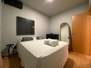 Un dormitorio con una gran cama blanca y un televisor de pantalla plana. en Ap Shopping Capim Dourado, en Palmas