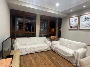 sala de estar con 2 sofás blancos y TV en Biescas Suites, en Biescas