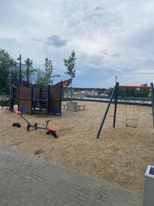 a playground with a swing set in the sand at Black & White Dziwnów in Dziwnów