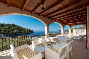 a balcony with white chairs and a view of the water at Villa Amfora Korcula - Six bedroom villa with amazing view in Blato