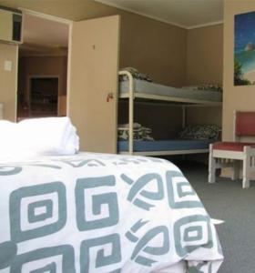 Zimmer mit einem Bett und Etagenbetten. in der Unterkunft Ahipara Holiday Park in Ahipara