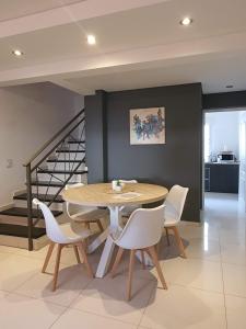 a dining room with a table and white chairs at Aguaribay Deptos Mendoza in Guaymallen