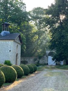 a stone building with a tower on a driveway at L'Écrin du Marquis in Bouvancourt