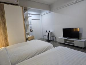 a bedroom with two beds and a flat screen tv at SRINN Hotel Pattaya Klang in Pattaya Central