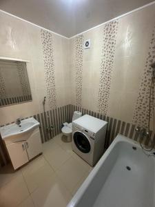 a bathroom with a tub and a toilet and a washing machine at 3 комнатная ЖК Альтаир in Aktobe