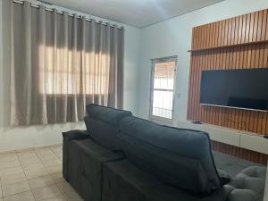un salon avec un canapé et une télévision à écran plat dans l'établissement Casa Belezas de Taquaruçu, à Palmas
