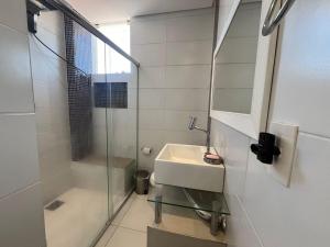 une salle de bain blanche avec lavabo et douche dans l'établissement Casa Palmas, à Governador Celso Ramos