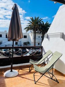 a patio with an umbrella and chairs on a balcony at Apartamento con amplia terraza en la playa in Puerto del Carmen +23 photos
