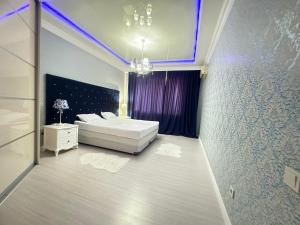 a bedroom with a white bed and a chandelier at Апартаменты 2 комнатная возле теннисного центра in Aktobe