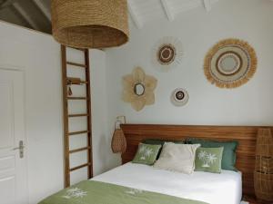a bedroom with a bed with green and white pillows at Villa Lola- Au cœur de la BO - 100m de la plage, cuve 800L in Orient Bay