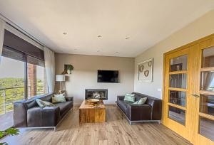 a living room with two leather couches and a fireplace at Villa Mar & Natura Sitges in Canyelles