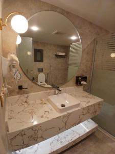 a bathroom with a sink and a mirror at شقق العنود والجوهرة للشقق المخدومة in Hafr Al Baten