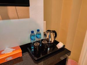a tray with a tea kettle and two bottles of water at Vitta Hotel Manokwari in Saowi