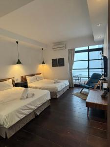 a hotel room with two beds and a desk and a chair at Playful House in Kenting