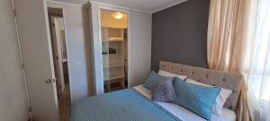 a bedroom with a bed with blue and white pillows at Montenegro 2 dormitorios in Temuco