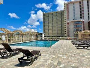 a swimming pool with lounge chairs and a hotel at Waikiki 30FL Luxury Studio with Majestic Ocean Fireworks in Honolulu